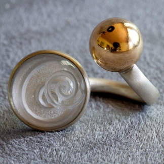 Offener Fingerring aus 925/-Silber mit einem Bergkristall mit eingeschliffener Spirale und 750/- Gelbgoldkugel